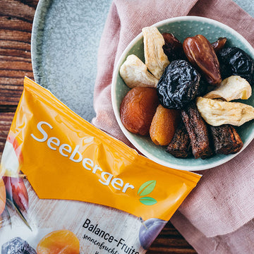 Eine Schale getrockneter Früchte neben einer Seeberger-Verpackung auf einem Holzuntergrund.