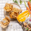 Muffins liegen auf einem Teller, umgeben von Karotten und Seeberger Nusskernmischung auf kariertem Tuch.